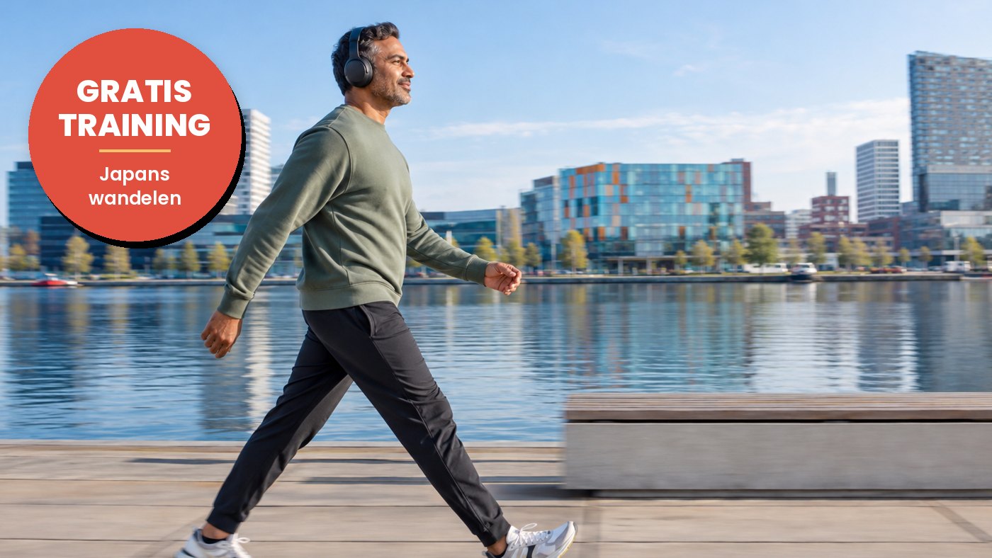 Man met koptelefoon wandelt stevig langs het water, met de stad op de achtergrond